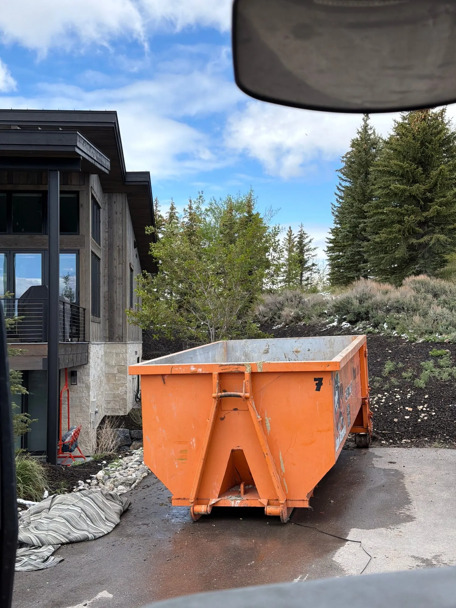 Orange dumpster in the driveway of a finished luxury mountain home